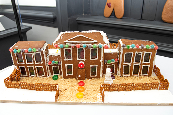 A giant two-story gingerbread house, with an east and a west wing. Over a dozen giant glazed sugar pane windows look out over the front of the property, which includes a pretzel fence around the house and path leading to it.
