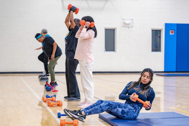 A group of people lifting small weights in a gymnasium.