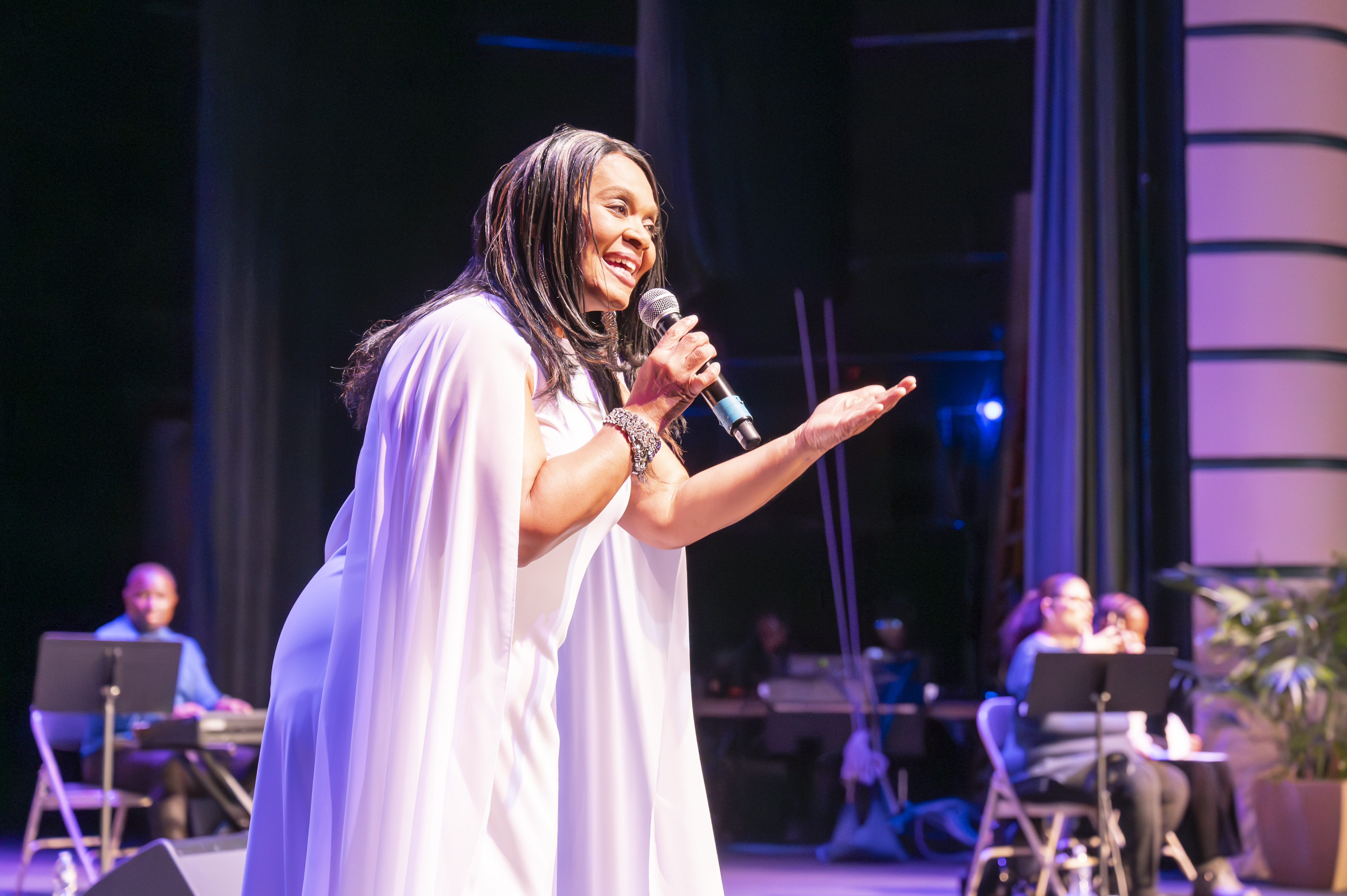 A woman on stage singing into a microphone