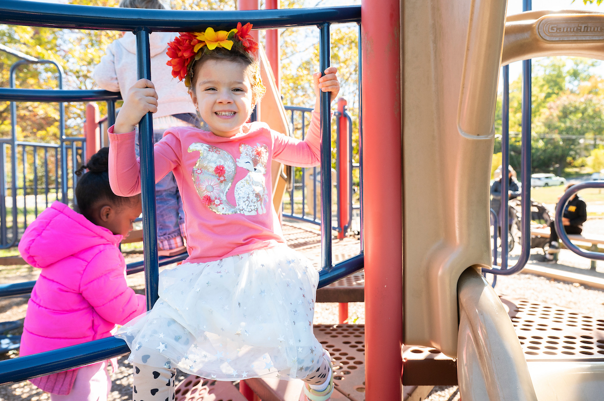 Kids play on the bridge element of a play structure on a playground.