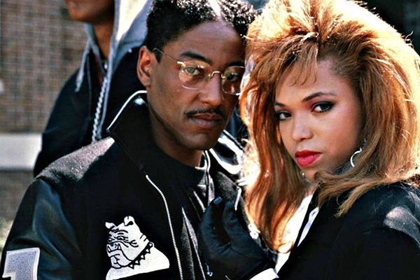 Publicity still from the film School Daze depicting a man and woman wearing matching high school letterman jackets embracing.