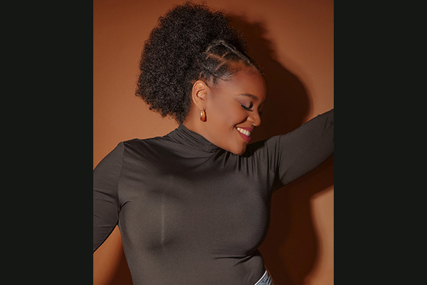 Promotional headshot of a smiling woman in a black shirt with her eyes closed.