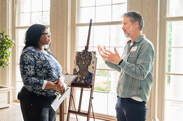 Visitor and presenter discuss artwork in a sunlit historic room during a heritage and preservation program.